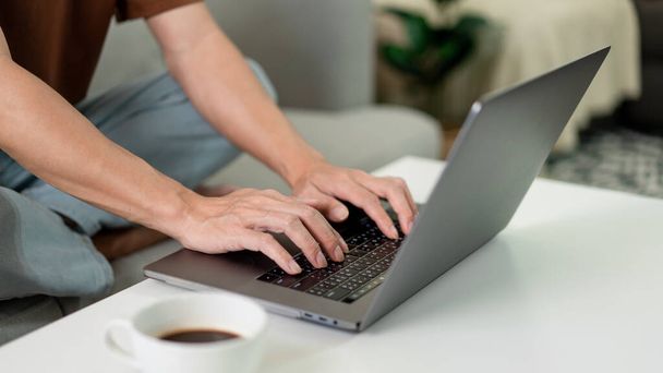 Technologie Koncept Muž v hnědém tričku se soustředí na psaní něčeho na svém notebooku. - Fotografie, Obrázek