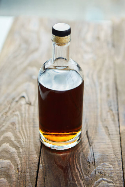 Alcoholic drink cognac or whiskey in a glass bottle on a wooden table. - Foto, Bild