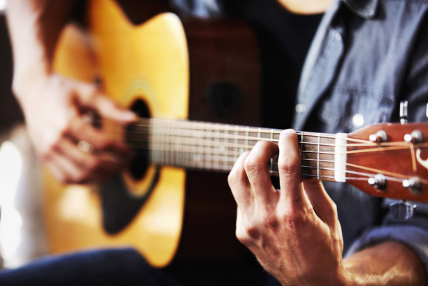 His skill has been gained through hours of practice. Cropped view of masculine hands strumming a guitar. - Photo, Image