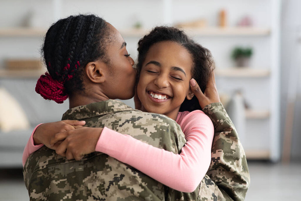 amorosa negro madre en militar uniforme besar hija - Foto, Imagen