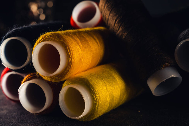 multi-colored spools of thread on a black background - Foto, Bild