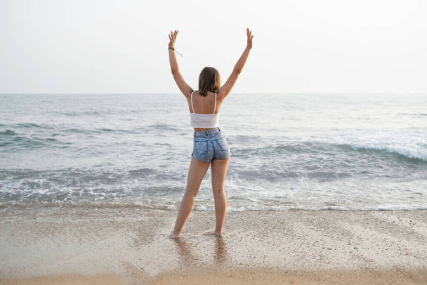 młoda kobieta z długimi włosami spacerująca po plaży - Zdjęcie, obraz