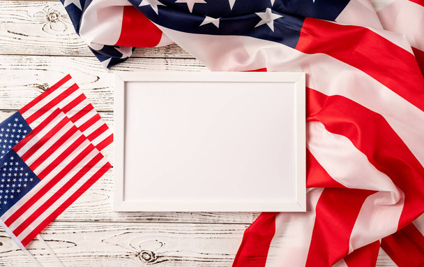 День памяти, День президентов США, День ветеранов, День труда или празднование 4 июля. Белая рамка для макета на деревянном фоне американского национального флага - Фото, изображение