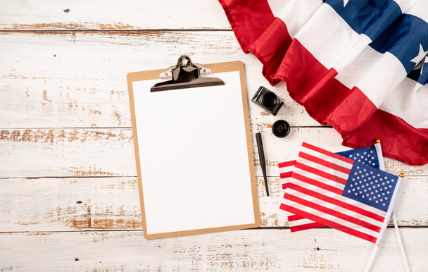 USA Memorial day, Presidents day, Veterans day, Labor day, or 4th of July celebration. Blank paper on craft clipboard for mockup design with USA flag and ink top view flat lay - Photo, Image