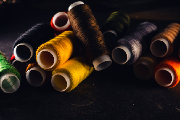 multi-colored spools of thread on a black background - Foto, Imagen