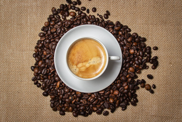 Café expreso en el fondo de granos de café y arpillera. Bebida tónica. Taza de café natural.  - Foto, imagen