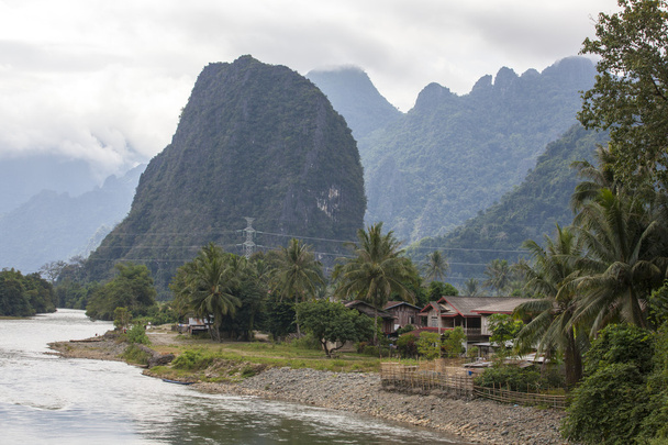 Дома и горы расположены вдоль побережья реки Нам песни Ванг Виенг, Лаос
. - Фото, изображение