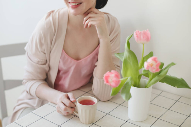 romantic spring portrait of a young woman with tulips at home. - Foto, imagen