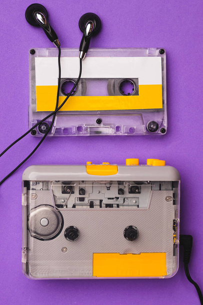 Reproductor de cassette con auriculares y cinta de cassette sobre fondo morado. - Foto, Imagen