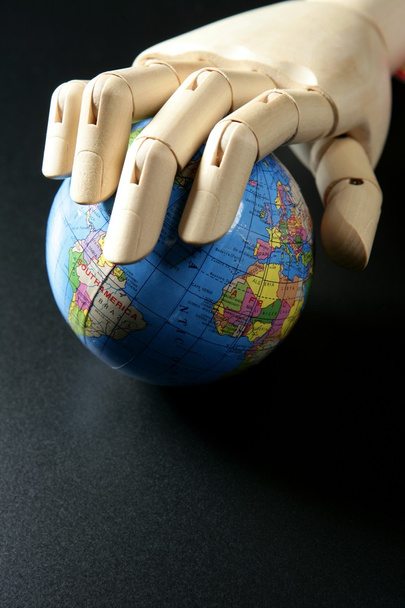 The world map in wood mannequin hand, black backgorund - Foto, afbeelding