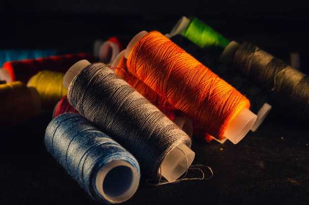 multi-colored spools of thread on a black background - Foto, Bild