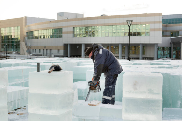 Bauarbeiter sägt mit Kettensäge eine Eisplatte - Foto, Bild