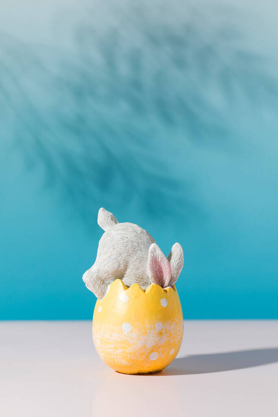 A white rabbit in an Easter egg on a blue background. The concept of a happy Easter. - 写真・画像