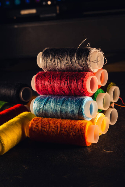 multi-colored spools of thread on a black background - Fotó, kép