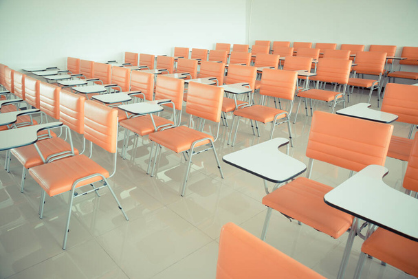 Vintage tono de las sillas de la escuela naranja en el fondo de las aulas vacías - Foto, Imagen