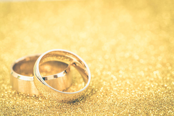Gold wedding rings of bride and groom on gold gliter background - Photo, Image