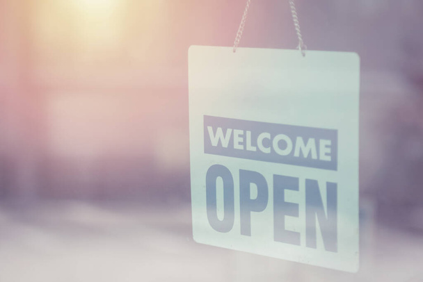Open and welcome sign broad through the glass of window to let customers know - Photo, Image