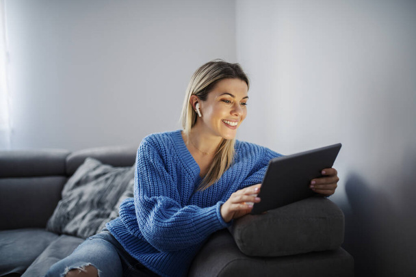 Una mujer feliz teniendo videollamada en la tableta en su acogedora casa. - Foto, imagen