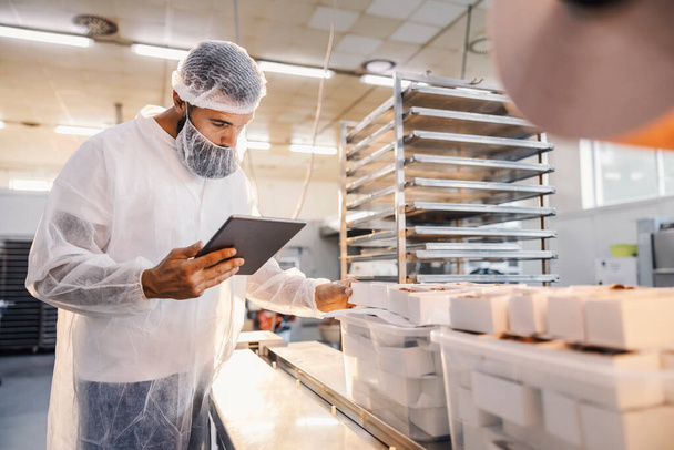Un superviseur d'usine alimentaire utilise une tablette et évalue la qualité des aliments. - Photo, image