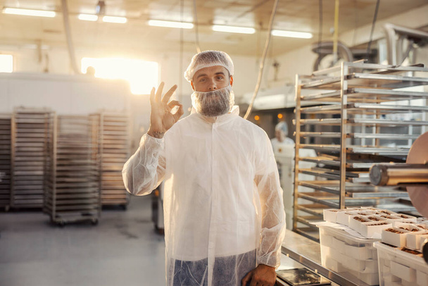 Un operaio di una fabbrica alimentare valuta la qualità dei prodotti con gesto manuale. - Foto, immagini