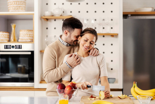 Una coppia felice prepara macedonia di frutta in cucina nel loro appartamento. - Foto, immagini