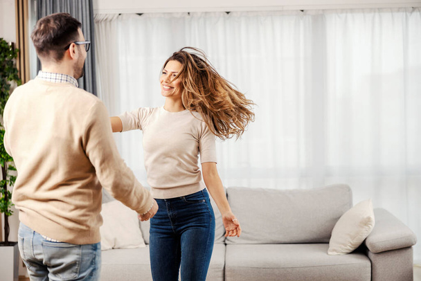 Счастливая пара танцует и веселится в своей новой уютной квартире. - Фото, изображение