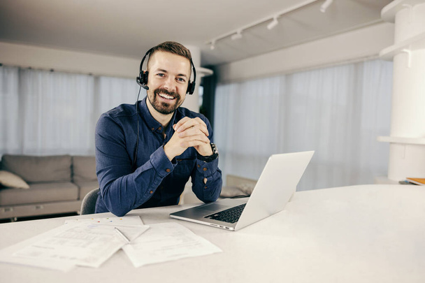 A happy man having conference call from his cozy home on the laptop and smiling at the camera. - Fotoğraf, Görsel