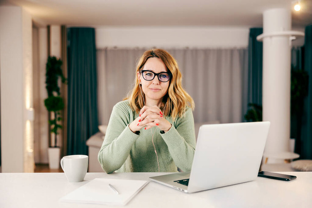 A successful businesswoman working from home and smiling at the camera. - Photo, Image