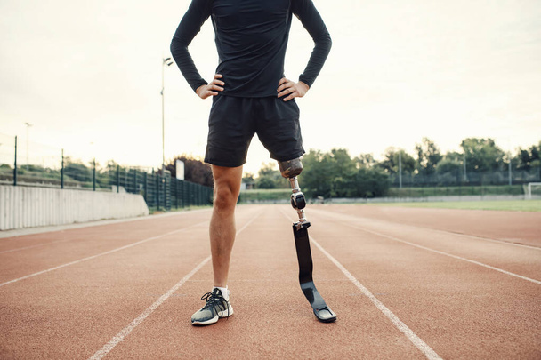 Bezbariérový běžec stojící na běžecké dráze na stadionu s rukama v bok. - Fotografie, Obrázek