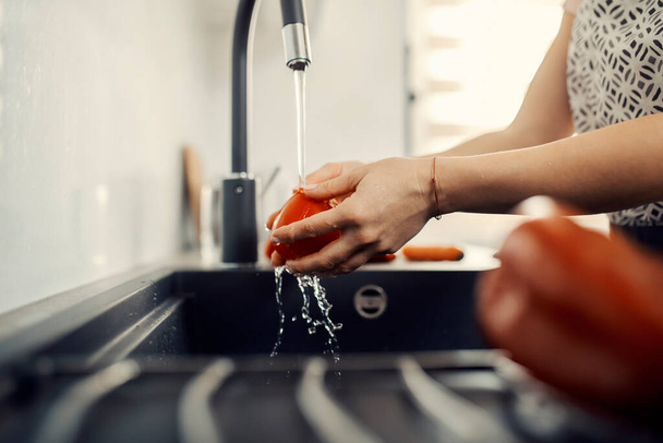Κοντινό πλάνο μιας νοικοκυράς που πλένει ντομάτα στο νεροχύτη. - Φωτογραφία, εικόνα