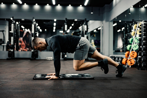 Un homme en forme fait des exercices d'échauffement sur un tapis dans une salle de gym. - Photo, image