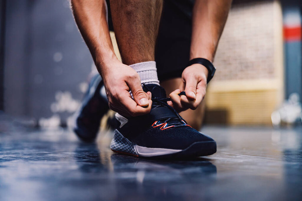 Close up of a male's hands tying shoelace in a gym. Sportsman preparing for a training. - Foto, afbeelding