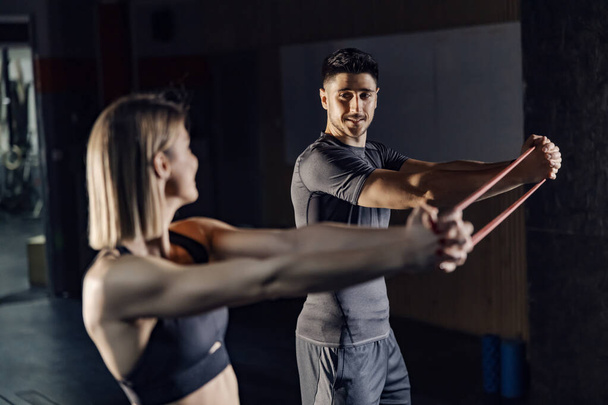 Ein glückliches Fitness-Paar trainiert mit Fitnessband im Fitnessstudio. - Foto, Bild