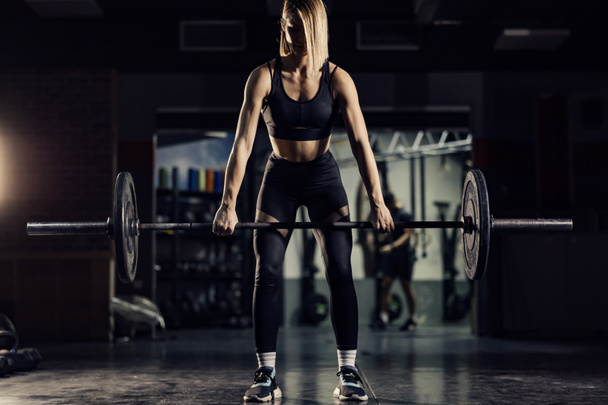 Uma mulher musculosa a exercitar-se e a levantar pesos num ginásio. Exercícios de força e vida saudável. - Foto, Imagem