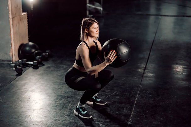 Сильная женщина делает функциональные упражнения с мячом в спортзале. - Фото, изображение