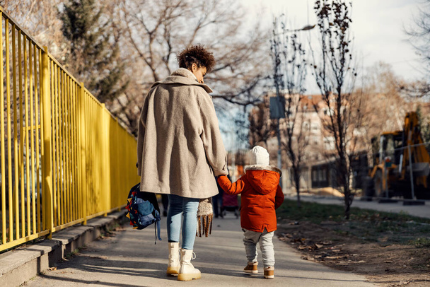 Uma babá ou cuidador andando menino para o jardim de infância para o primeiro dia na escola. - Foto, Imagem