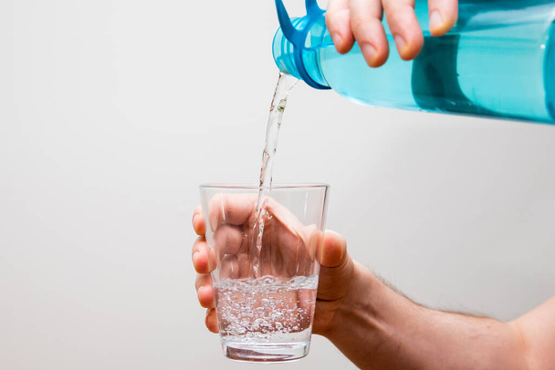 mano sosteniendo un vaso de agua con un fondo blanco - Foto, imagen