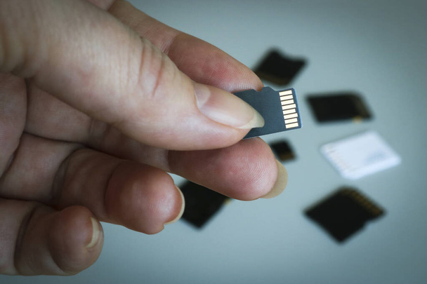 MicroSD geheugenkaart in de hand tegen een wazige achtergrond van andere SD-geheugenkaarten. - Foto, afbeelding