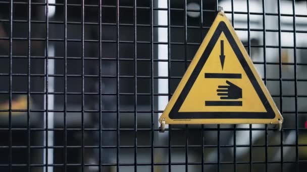 Panneau de danger de machine d'usine avec icône de main sur fond de mécanisme de convoyeur de grille - Séquence, vidéo
