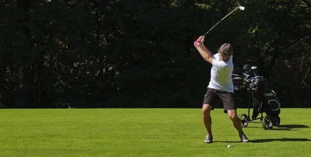 Golfista en un campo de golf en el verano en un día soleado, golpeando la pelota con un club de golf. - Foto, Imagen