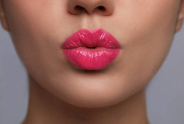 Primo piano vista di bella donna puckering labbra per bacio su sfondo grigio - Foto, immagini
