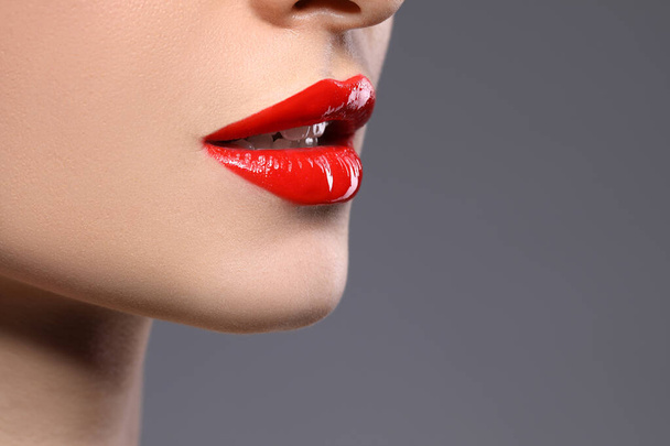 Young woman with beautiful red lips on grey background, closeup. Space for text - Foto, afbeelding