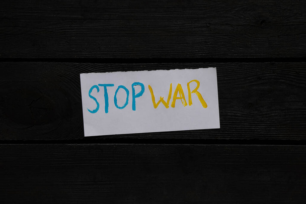 Pare a guerra escrita em amarelo-azul em um pedaço de papel branco em um fundo isolado, paz na Ucrânia, ação de protesto, banner - Foto, Imagem