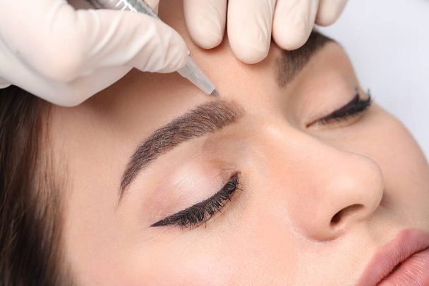 Young woman during procedure of permanent eyebrow makeup, closeup - Zdjęcie, obraz