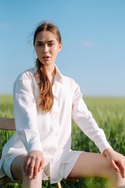 Young  woman  in white suit posing in green wheat field. Fashion and lifestyle concept. People, travel, nature and vacations concept. - Zdjęcie, obraz