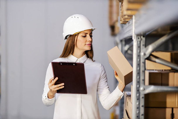 Женщина-супервайзер держит планшет и смотрит на коробку с товарами, готовыми к отправке. - Фото, изображение