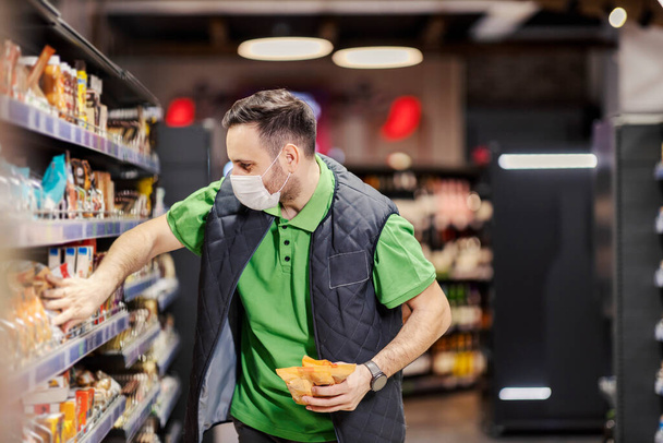 An employee putting groceries on aisle at supermarket during covid 19. - Fotoğraf, Görsel