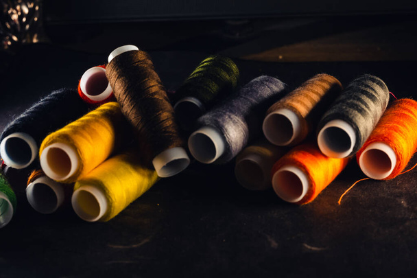 multi-colored spools of thread on a black background - 写真・画像