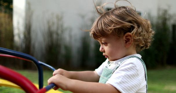 Cute baby maluch przędzenia na karuzeli w parku placu zabaw - Zdjęcie, obraz
