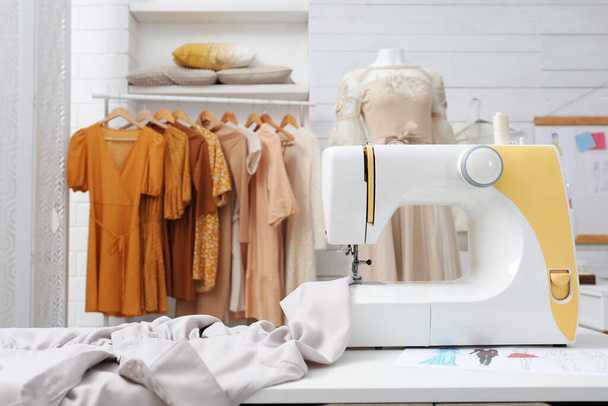 Modern sewing machine with fabric on table in dressmaking workshop - Valokuva, kuva